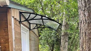 En stuga byggd av trä med en överbyggd veranda och en grusgång som leder fram till dörren.