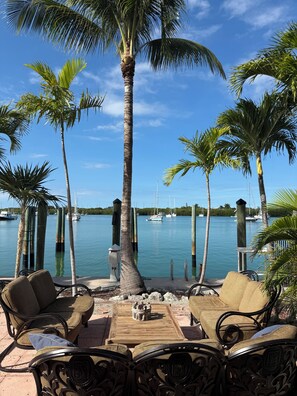 Une terrasse au bord de l’eau, dotée de mobilier d’extérieur et offrant une vue sur le port de plaisance.