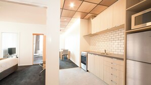 A modern kitchen with wooden cabinets, a stainless steel refrigerator, and a microwave. - Liberty Apartment Hotel (Wellington)