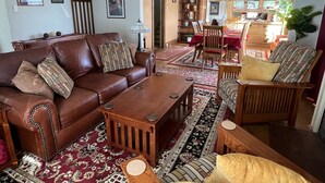 Ein gemütliches Wohnzimmer mit einem braunen Ledersofa, einem Holztisch und gemusterten Teppichen.