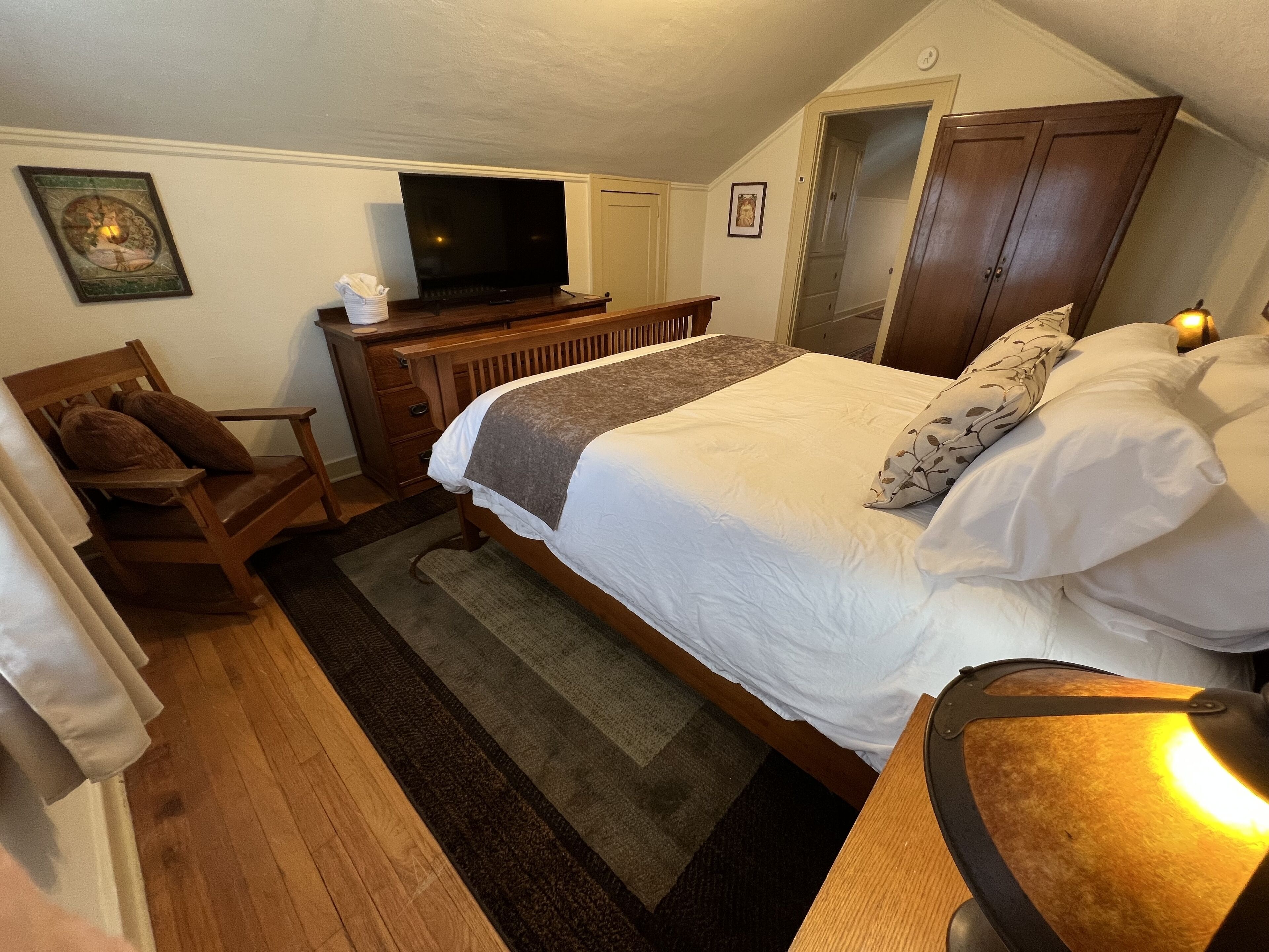 Un dormitorio con cama, cómoda de madera, televisor y una silla.