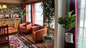Ein gemütliches Wohnzimmer mit Essbereich, mit Holzkunst, einer großen Topfpflanze und Blick durch eine Bogenöffnung.