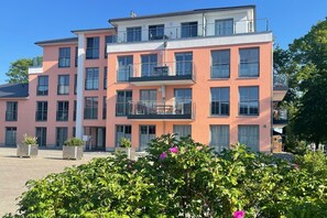 Un immeuble résidentiel à plusieurs étages, doté de balcons, de grandes fenêtres et d’une cour pavée.