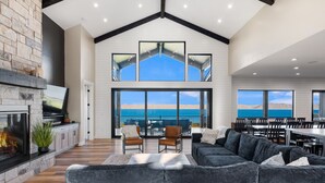 A spacious living area with a fireplace, a large sofa, and a dining area with a view of the ocean.