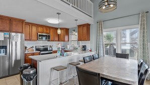 Een moderne keuken met houten kastjes, roestvrijstalen apparatuur en een groot eiland met barkrukken.