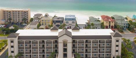 A multi-story hotel with a central courtyard, parking lot, and ocean view.