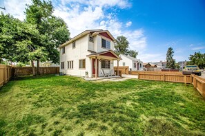 A two-story house with a covered porch, a fenced backyard, and a clear blue sky. - #HabitueHomes  - The Touchdown - Near BSU! (Boise)