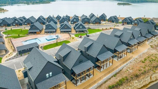 Een rij moderne cabins met een zwembad en uitzicht op een meer.