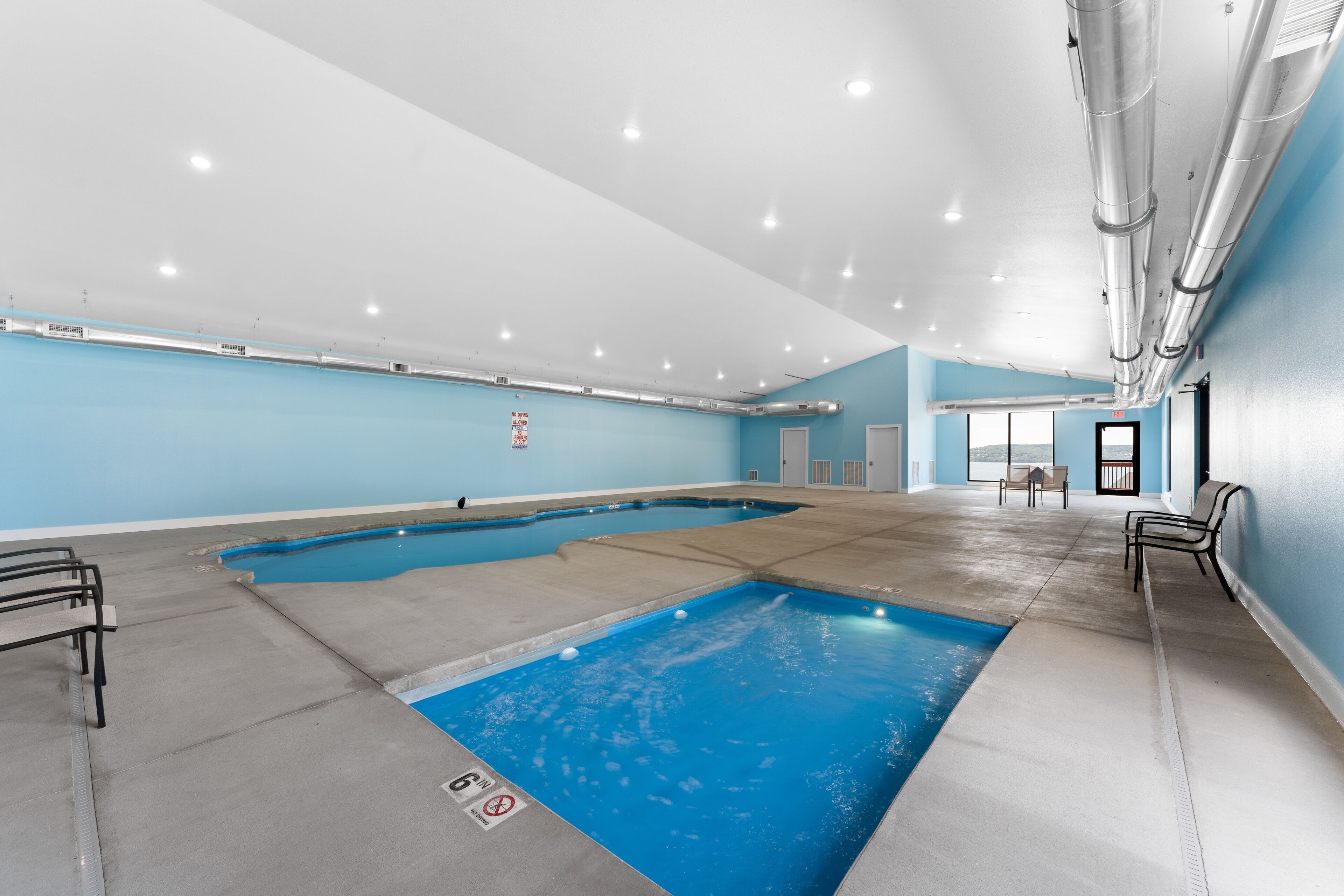 Una piscina interior amb aigua cristal·lina, una paret blava i un sostre amb il·luminació empotrada.