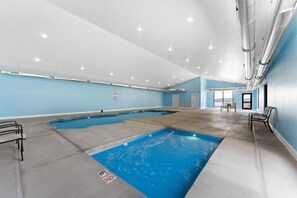 An indoor swimming pool with clear water, a blue wall, and a ceiling with recessed lighting. - Cedar Shores 7 Bedroom Home by RedAwning (Hollister)