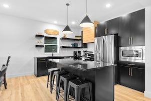 A modern kitchen with black cabinets, stainless steel appliances, and a central island with bar stools.