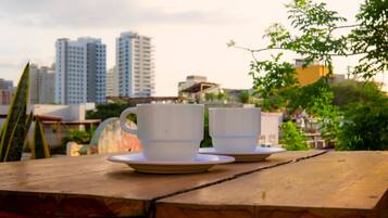 Two white cups on a wooden table with a cityscape in the background.