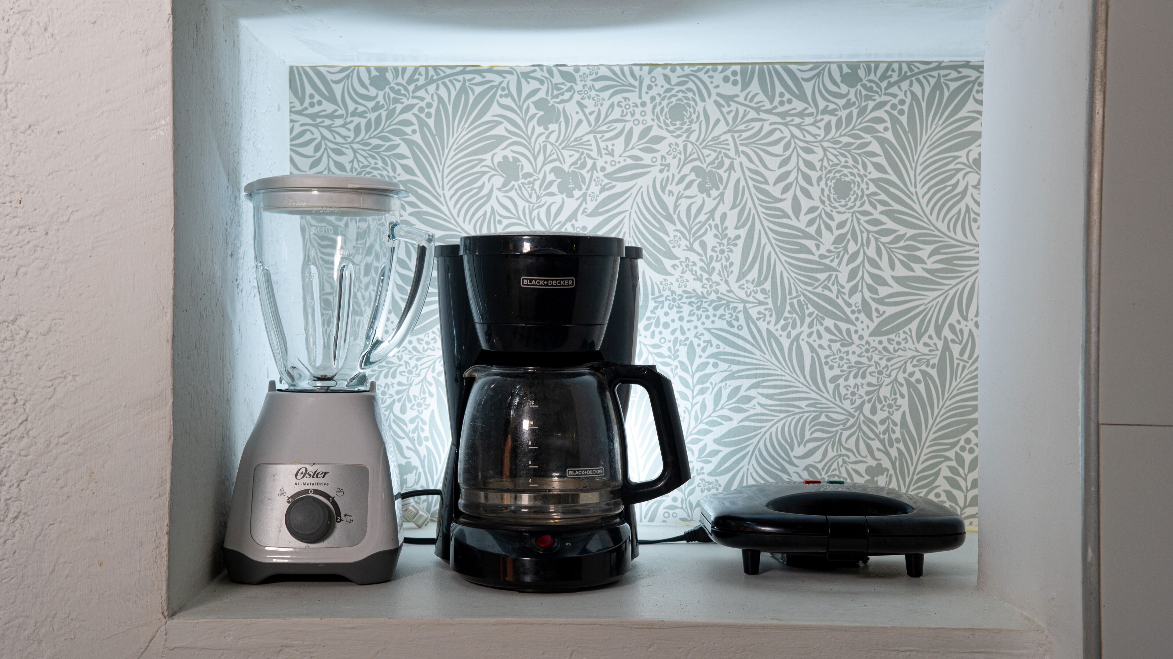 A kitchen with a blender and a coffee maker on the counter.