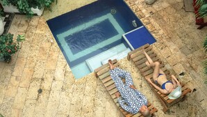 A pool area with two wooden loungers, one occupied by a person in a patterned outfit and another by a person in a bikini. - 6 Bedroom Charming Colonial House With Pool (Santa Marta)