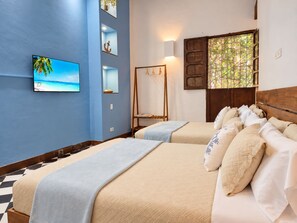 Une chambre d’hôtel avec deux lits, une télévision, une fenêtre donnant sur un paysage agréable et des éléments de décoration fixés au mur.