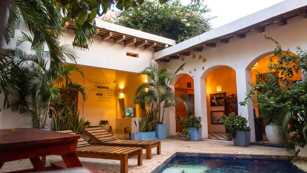 A courtyard with a pool, wooden benches, and potted plants. - 6 Bedroom Charming Colonial House With Pool (Santa Marta)