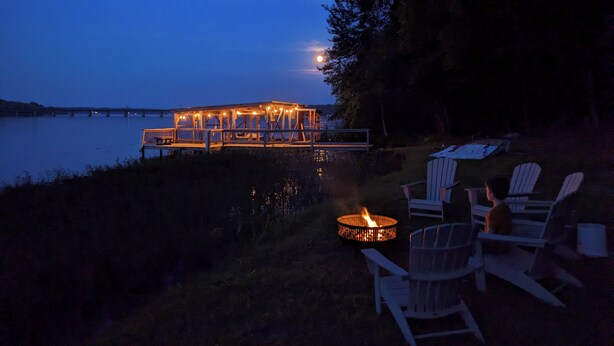 A lakeside deck with outdoor seating and a fire pit.
