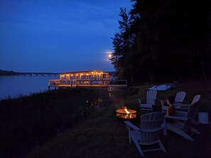 A lakeside deck with outdoor seating and a fire pit.