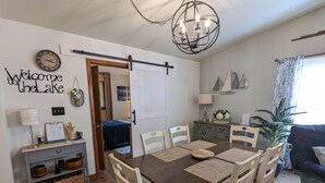 A dining area with a wooden table, white chairs, and a chandelier.