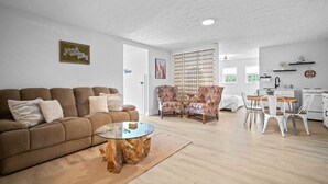 A modern living room with a brown sofa, a glass coffee table, and patterned armchairs. - Luxury pet-friendly remodeled cottage (Sparta)