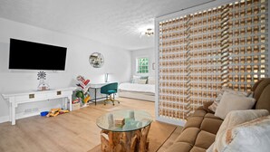 A modern living room with a flat-screen TV, a wooden coffee table, a sofa, and a decorative wall panel. - Luxury pet-friendly remodeled cottage (Sparta)
