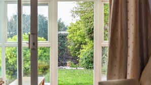 A room with a large glass door leading to a garden.
