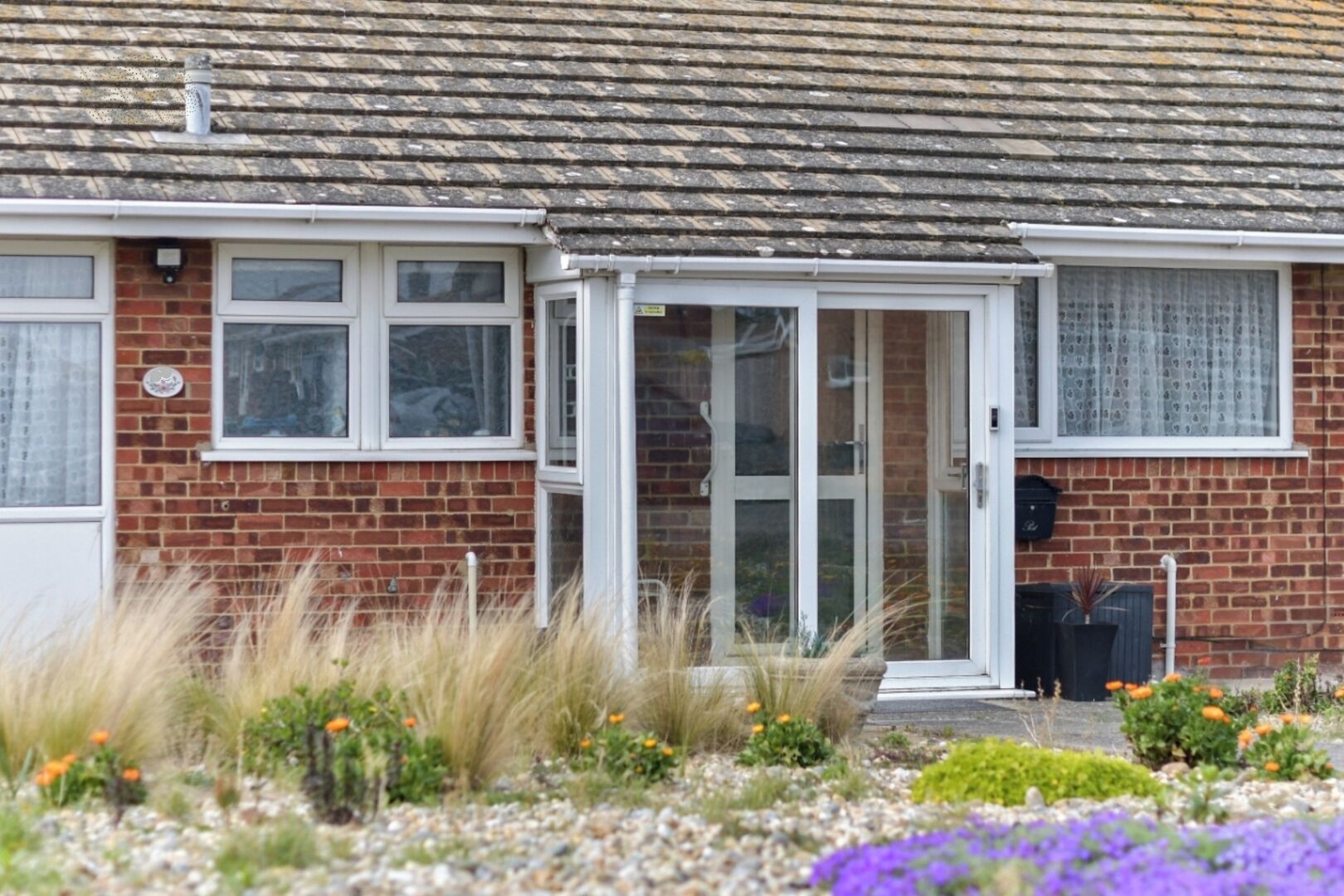 A residential house with a brick exterior, a tiled roof, and a front door.