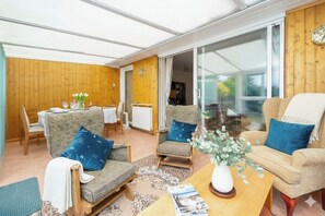 A cozy room with a dining area, two armchairs, a coffee table, and a large window. - Amazing Beachside 2BD Family Home with Garden (Cliftonville)