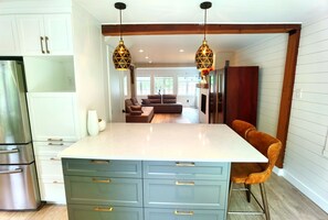 A modern kitchen with a central island, white cabinets, and a stainless steel refrigerator. - lacbrome Chalet lake+Terrasse+BBQ+Hot-tub (Foster)