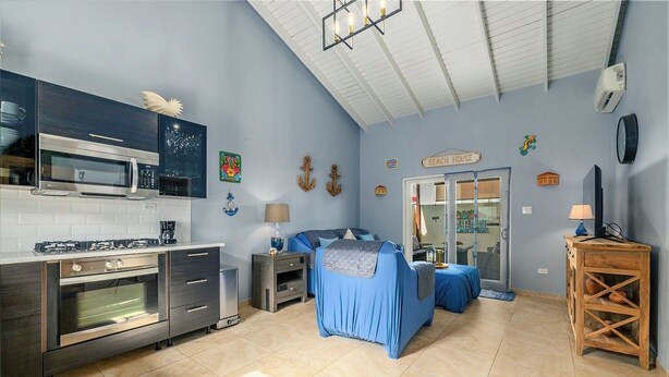 Una cucina compatta con elettrodomestici moderni, un letto con copriletto blu e arredamento a tema spiaggia.