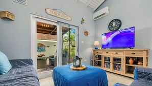 Una stanza con un letto, una TV, un mobile pieno di libri e un cartello con su scritto 'BEACH HOUSE'.