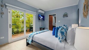 Una camera da letto con un letto, una televisione, una porta e vista su palme.