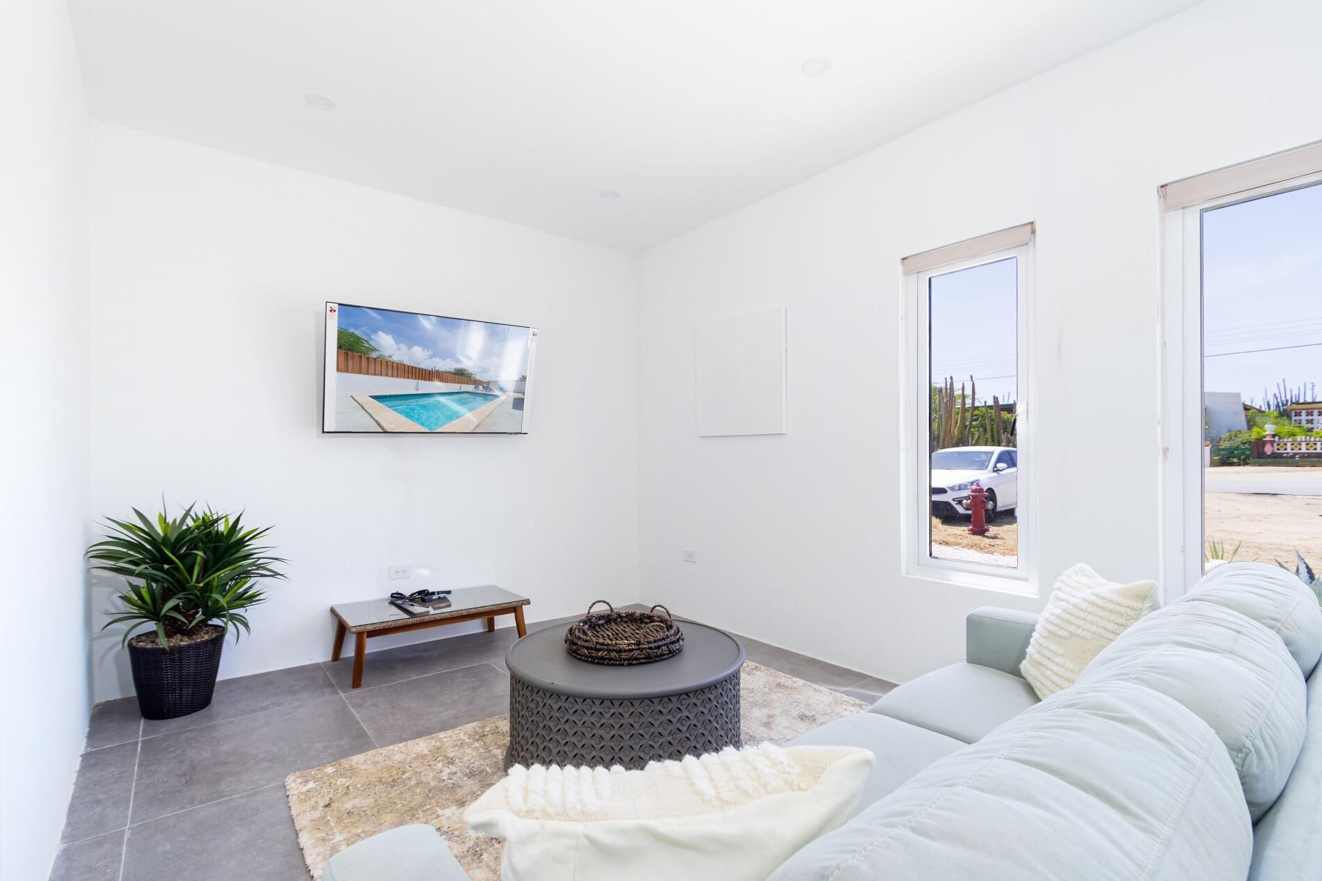 Un salon moderne avec vue sur la piscine, un canapé, une table basse et une plante en pot.