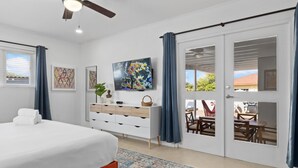 A bedroom with a bed, a dresser, a TV, and a view of the outside. - Beautiful 3BR2BA, Amazing Location w/ Private Pool (Noord)