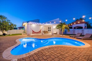 A swimming pool with a covered patio area, lounge chairs, and string lights. - Beautiful 3BR2BA, Amazing Location w/ Private Pool (Noord)