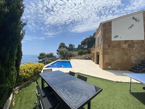 Enjoy a tranquil coastal escape with a balcony overlooking the sea, a swimming pool, and outdoor dining area.