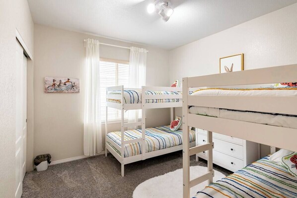 A bunk bed room with a window, curtains, a framed picture, and a small white cabinet. - The Park House, Cozy Family-Friendly Retreat (Brighton)