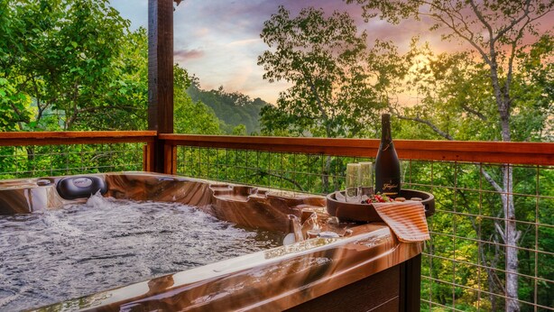 Un bain à remous avec une terrasse en bois et une vue sur une végétation luxuriante.