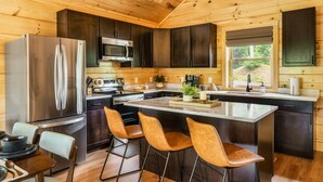 Une cuisine moderne avec des murs en bois, des appareils électroménagers en acier inoxydable et un îlot central doté de tabourets de bar.