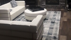 En stue med en hvid sofa, en sort lænestol, en pejs og et billede på væggen.