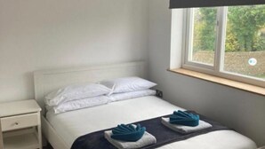 A neatly made bed with white linens and two folded towels on the side. - Lovely 5-Bed House in Brighton (Brighton)