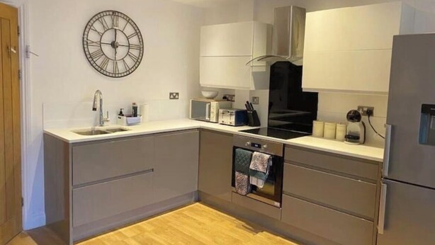A modern kitchen with a built-in oven, a coffee maker, and a clock on the wall. - Lovely 5-Bed House in Brighton (Brighton)