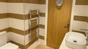 A bathroom with striped tile walls, a wooden door, a towel rack, and a sink. - Lovely 5-Bed House in Brighton (Brighton)