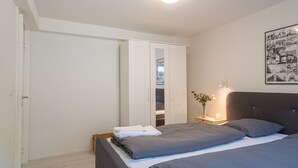 A bedroom with a bed, a wardrobe, a bedside table with a lamp, and a framed picture on the wall. - Newly renovated 1-Bed Apartment in Aalborg (Aalborg)