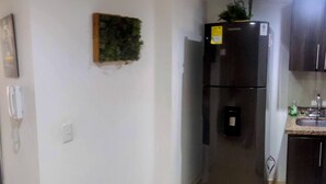 A compact kitchen with a refrigerator, a small sink, and a wall-mounted telephone. - Great Location: Apartment Nearby Itagui Metro Station (Sabaneta)