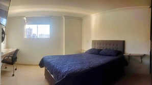 A bedroom with a bed, a desk, and a window with a city view. - Great Location: Apartment Nearby Itagui Metro Station (Sabaneta)