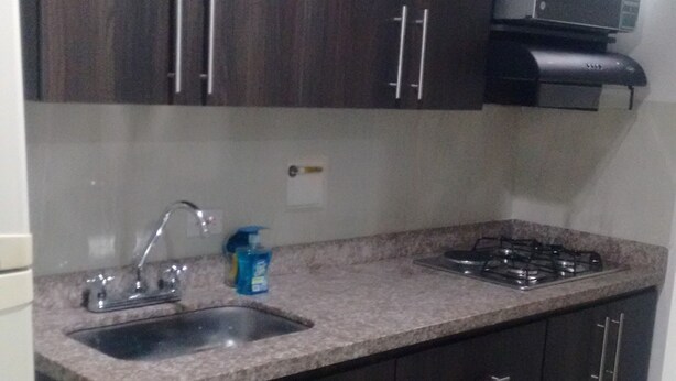 A kitchen with dark wooden cabinets, a granite countertop, a stainless steel sink, and a gas stove. - Great Location: Apartment Nearby Itagui Metro Station (Sabaneta)