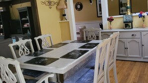 A dining area with a long table, white chairs, and a wooden floor.