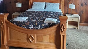 A wooden bed with a floral bedspread, two bedside tables, and a window with curtains.