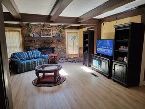 A living room with a stone fireplace, a sofa, a coffee table, and a television.